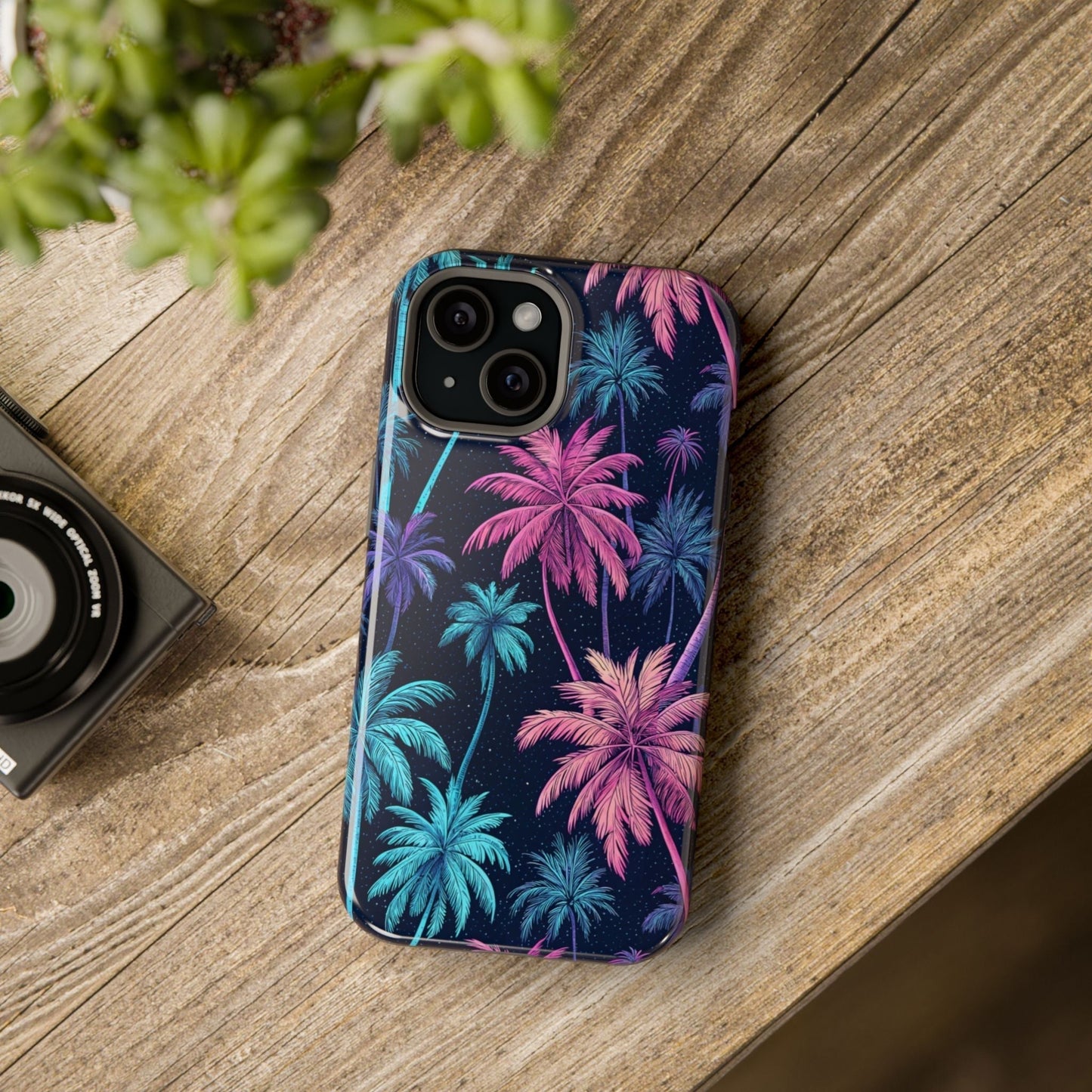 iPhone case with neon pink and blue palm trees design and MagSafe compatibility on wooden surface