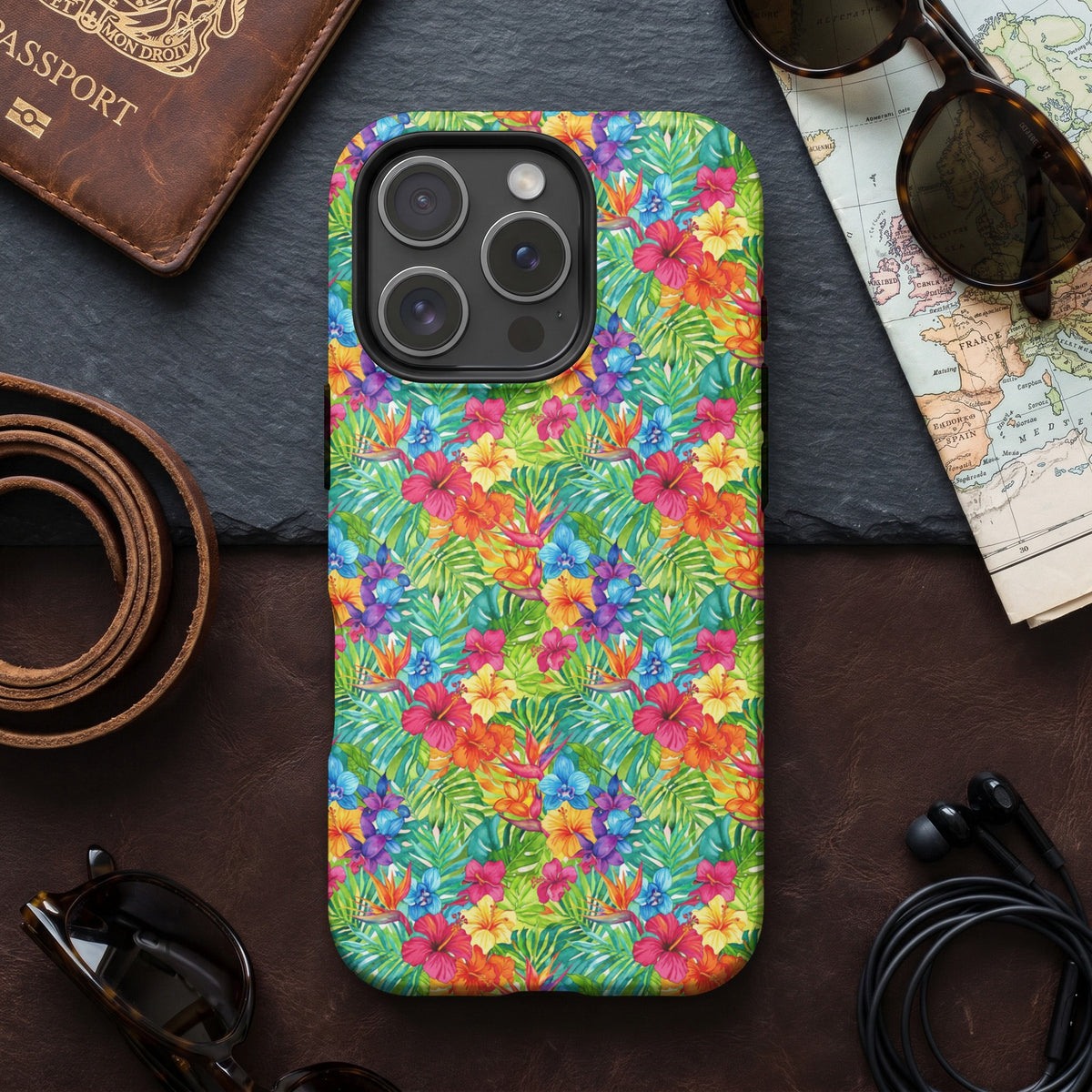 Phone case with a colorful tropical floral print, passport, sunglasses, and map.