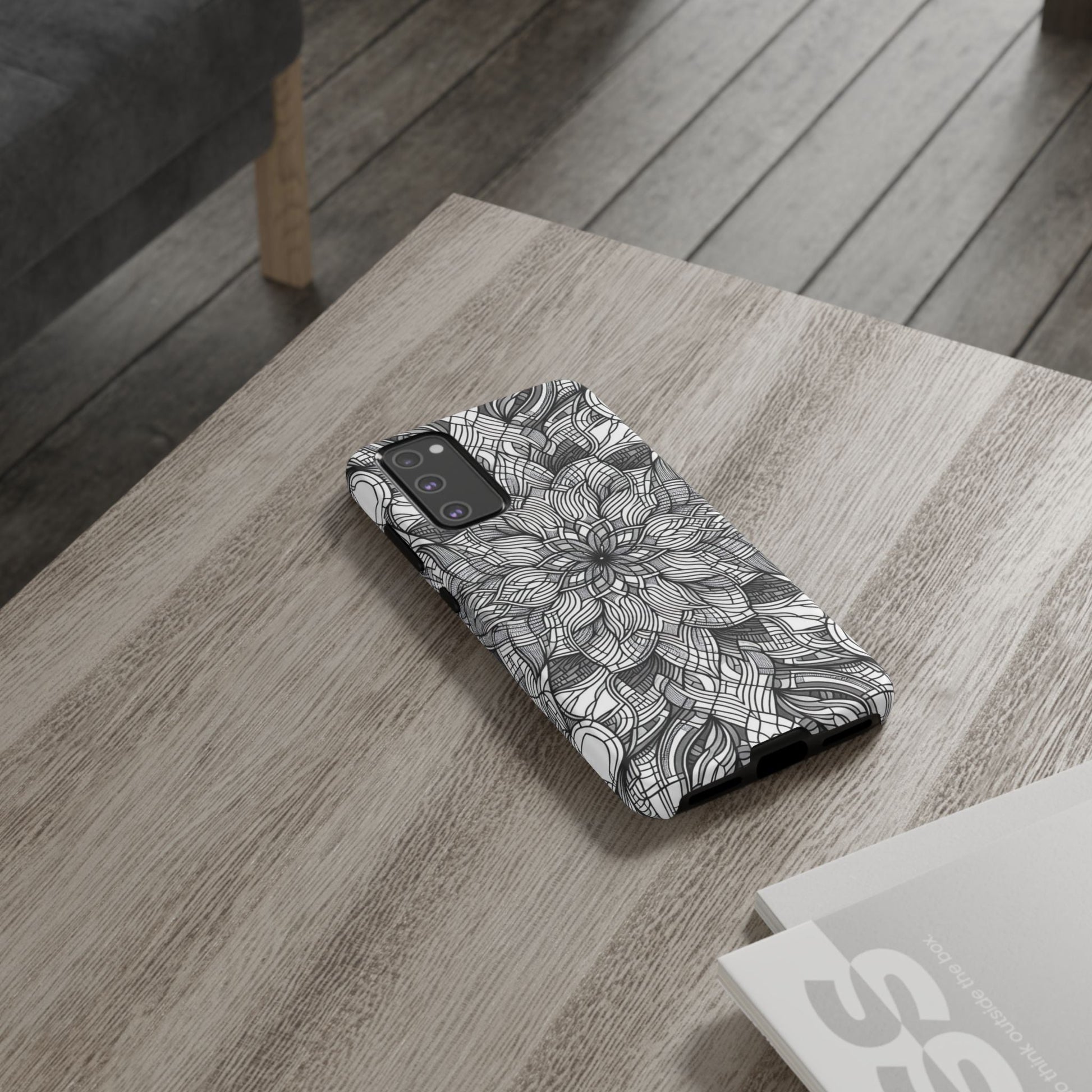 Samsung phone case with black and white intricate floral art explosion design on wooden table