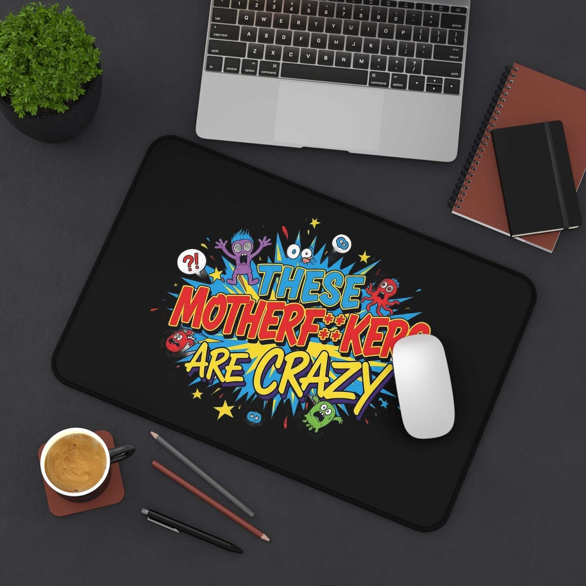 Black desk pad with colorful "These Motherf++kers Are Crazy" text and cartoon characters, non-slip and durable design