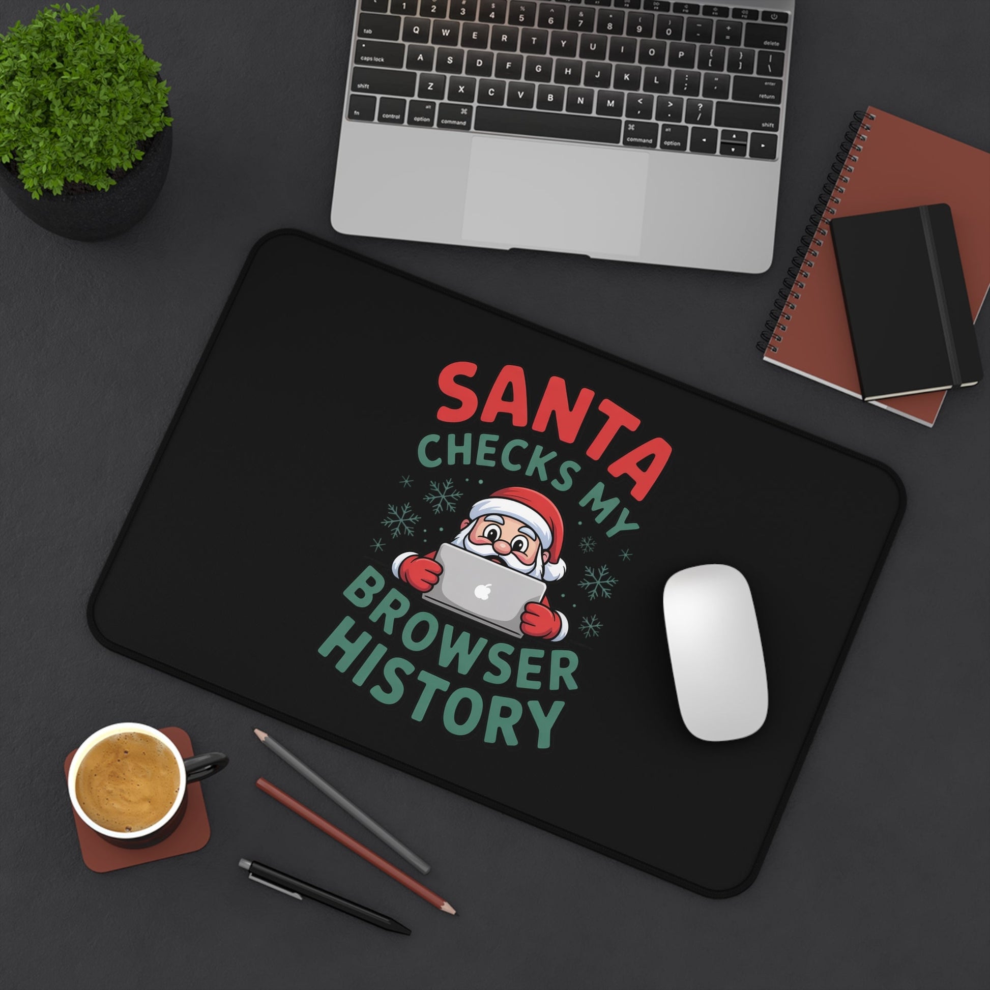 Funny Santa Desk Mat with Santa checking browser history in festive colors, placed on desk with laptop, mouse, coffee, and stationery.