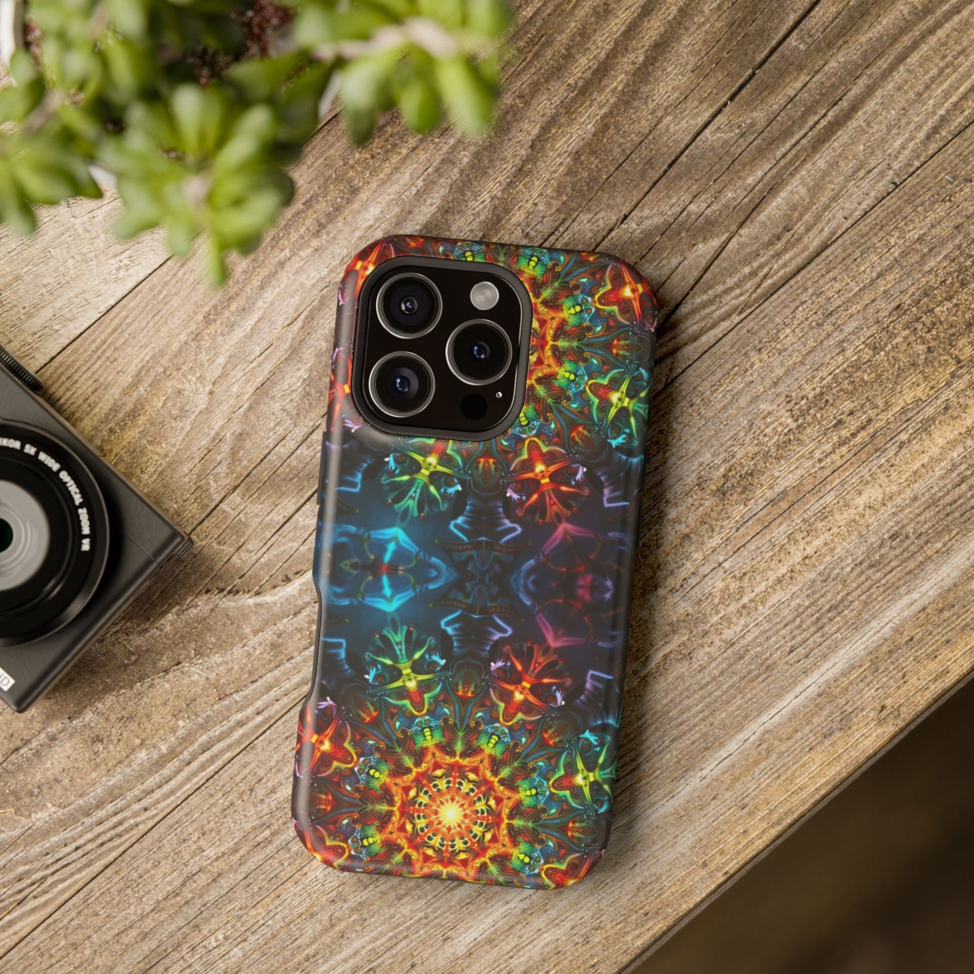iPhone case with vibrant abstract kaleidoscope design on wooden surface, showcasing colorful geometric patterns and triple camera cutout