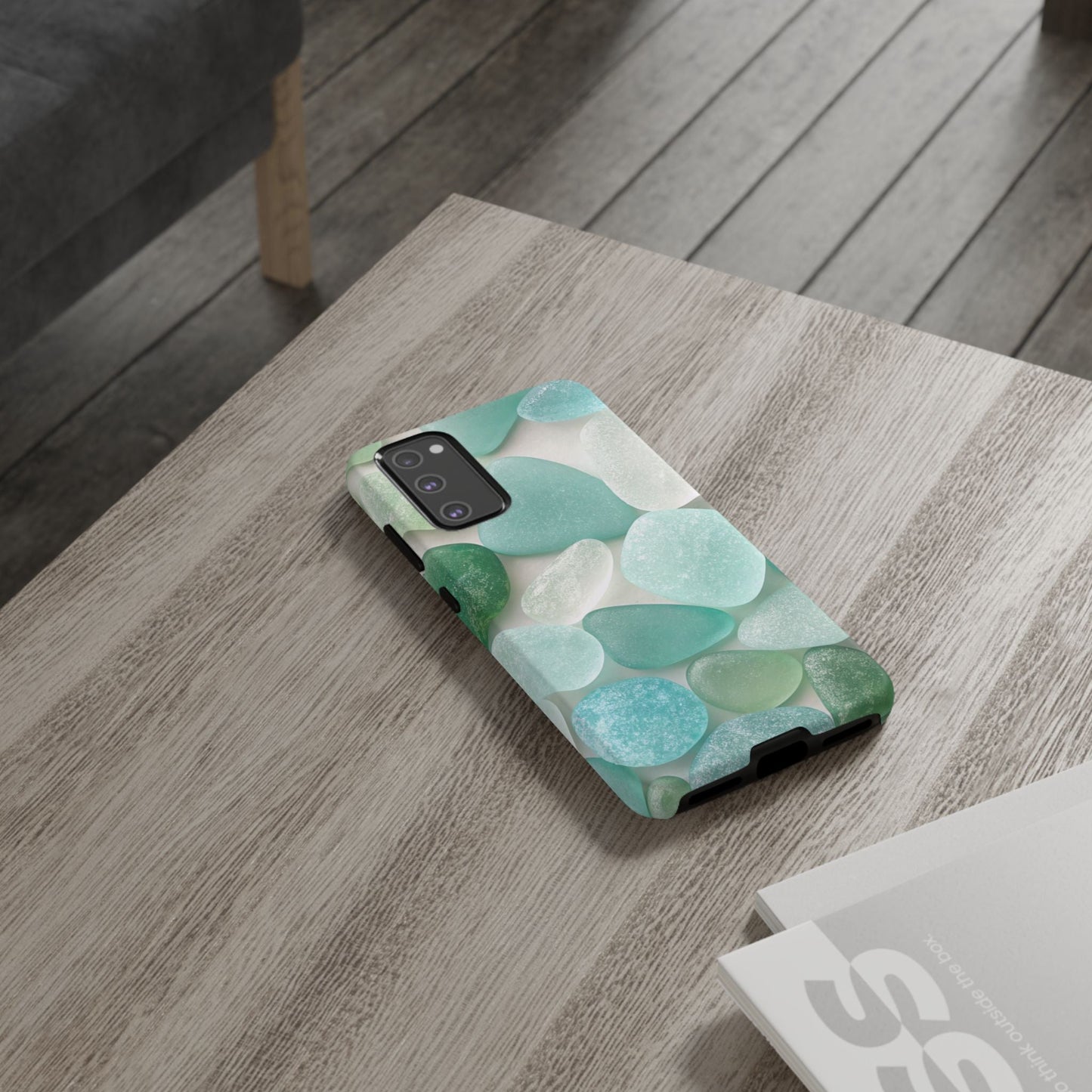 Samsung phone case with calming sea glass design in shades of blue and green on a wooden table
