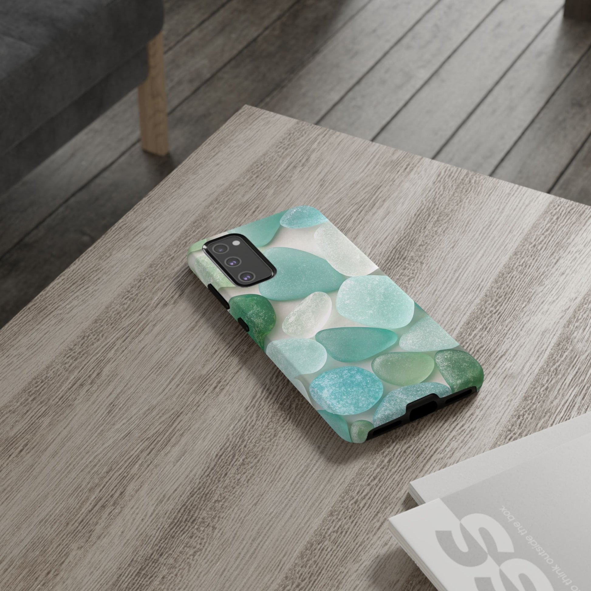 Samsung phone case with calming sea glass design in shades of blue and green on a wooden table