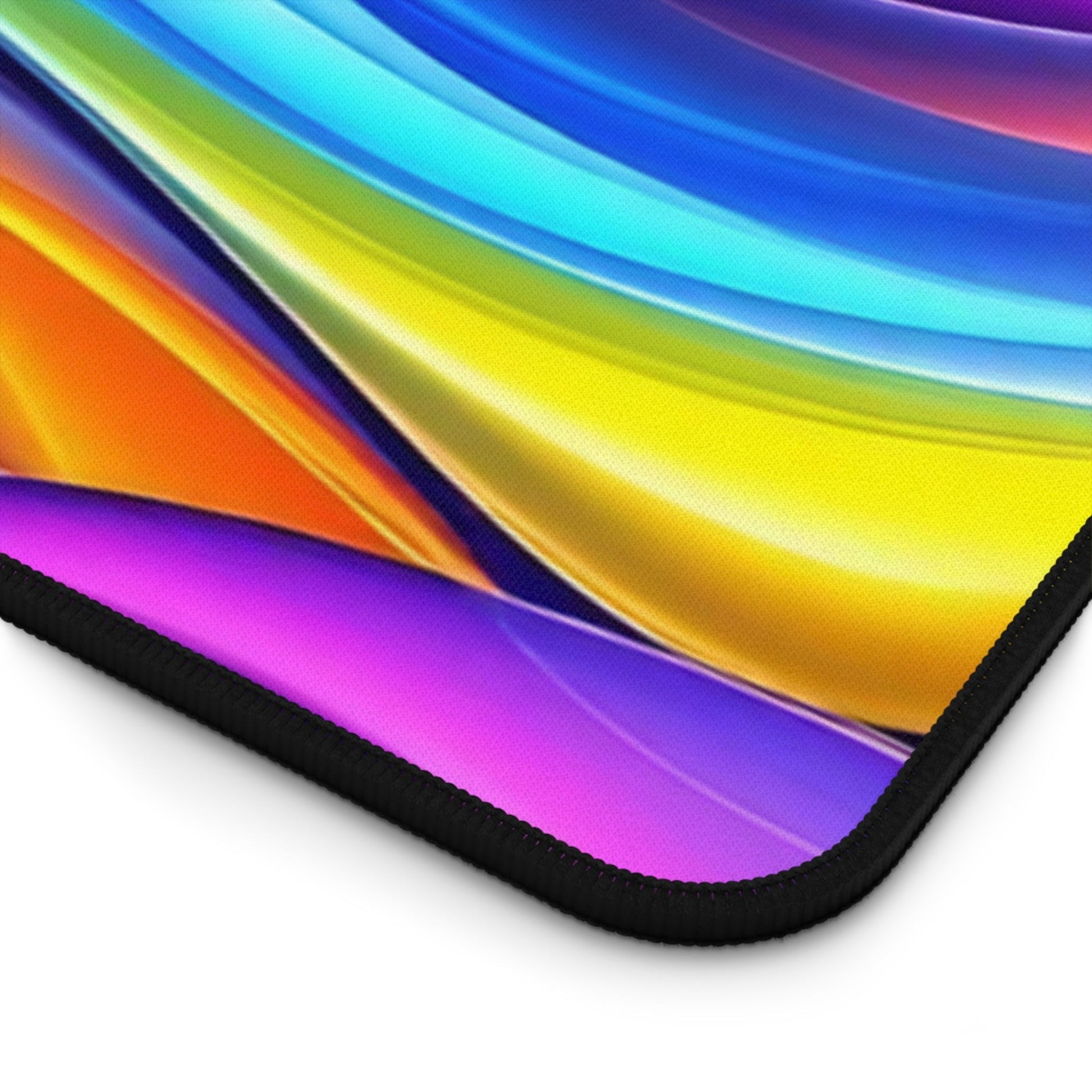Close-up of a Modern Rainbow Waves desk mat corner with vibrant colorful waves and black hemmed edges