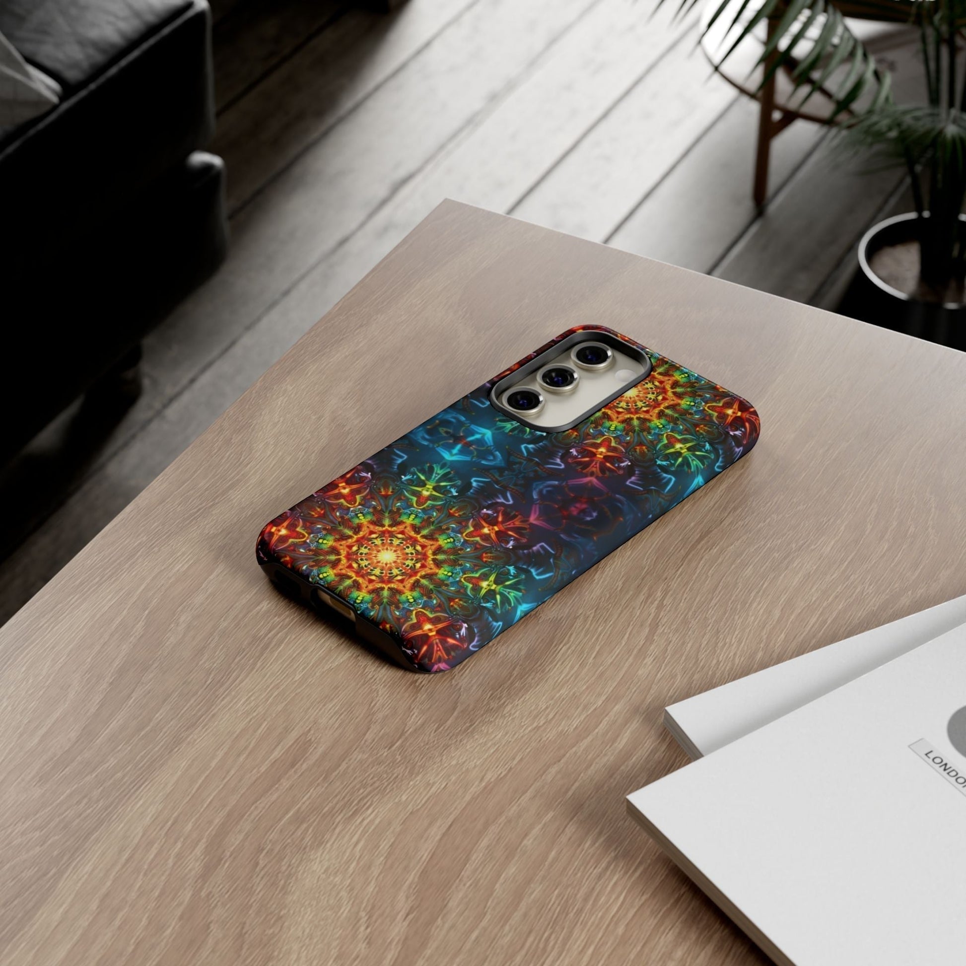 Colorful abstract kaleidoscope design Samsung phone case on wooden table next to books