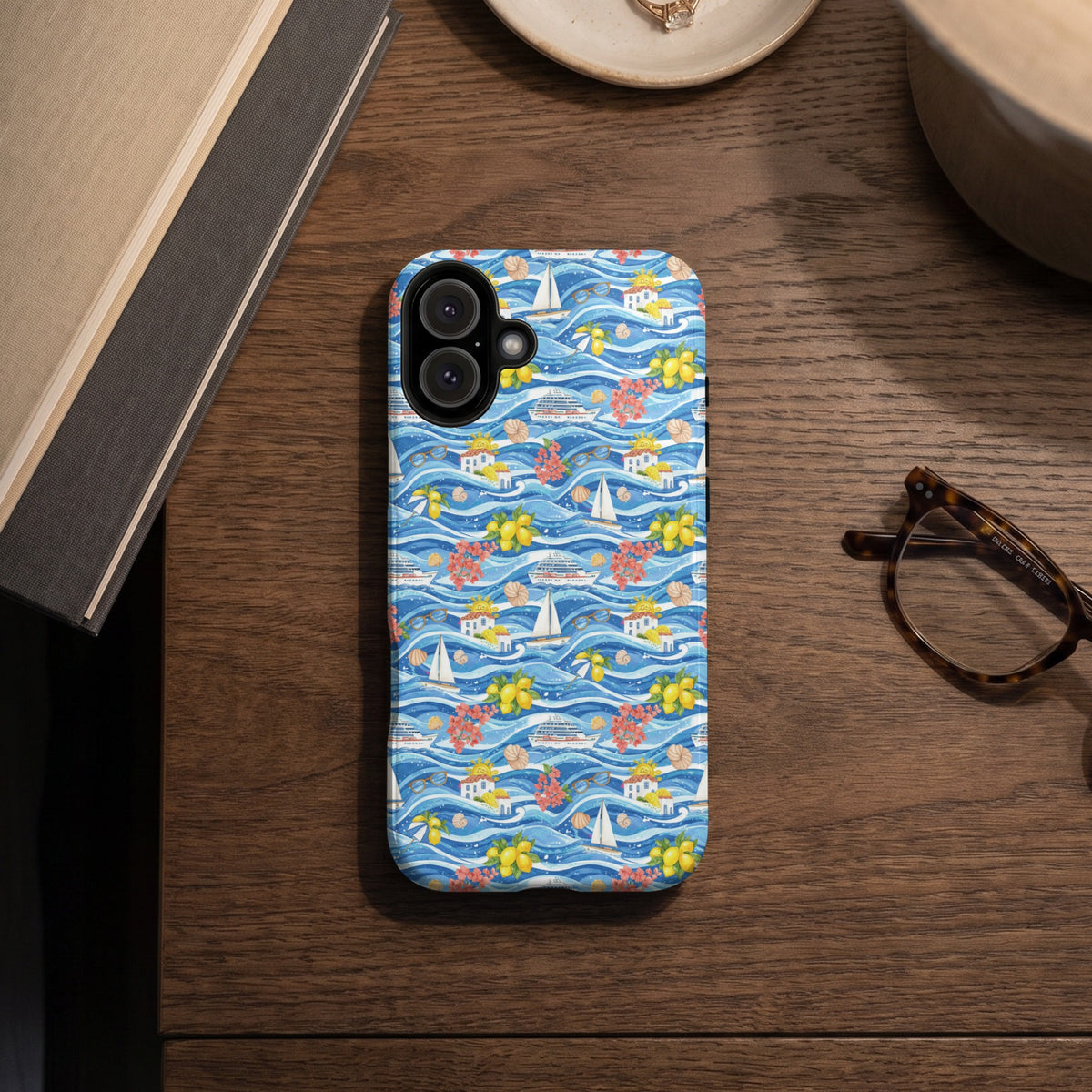 Phone case with a blue wavy pattern featuring boats, lemons, flowers, and houses.