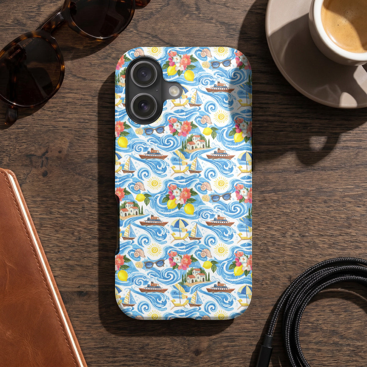 Phone case with a seaside village, boats, lemons, flowers, and sunglasses pattern.