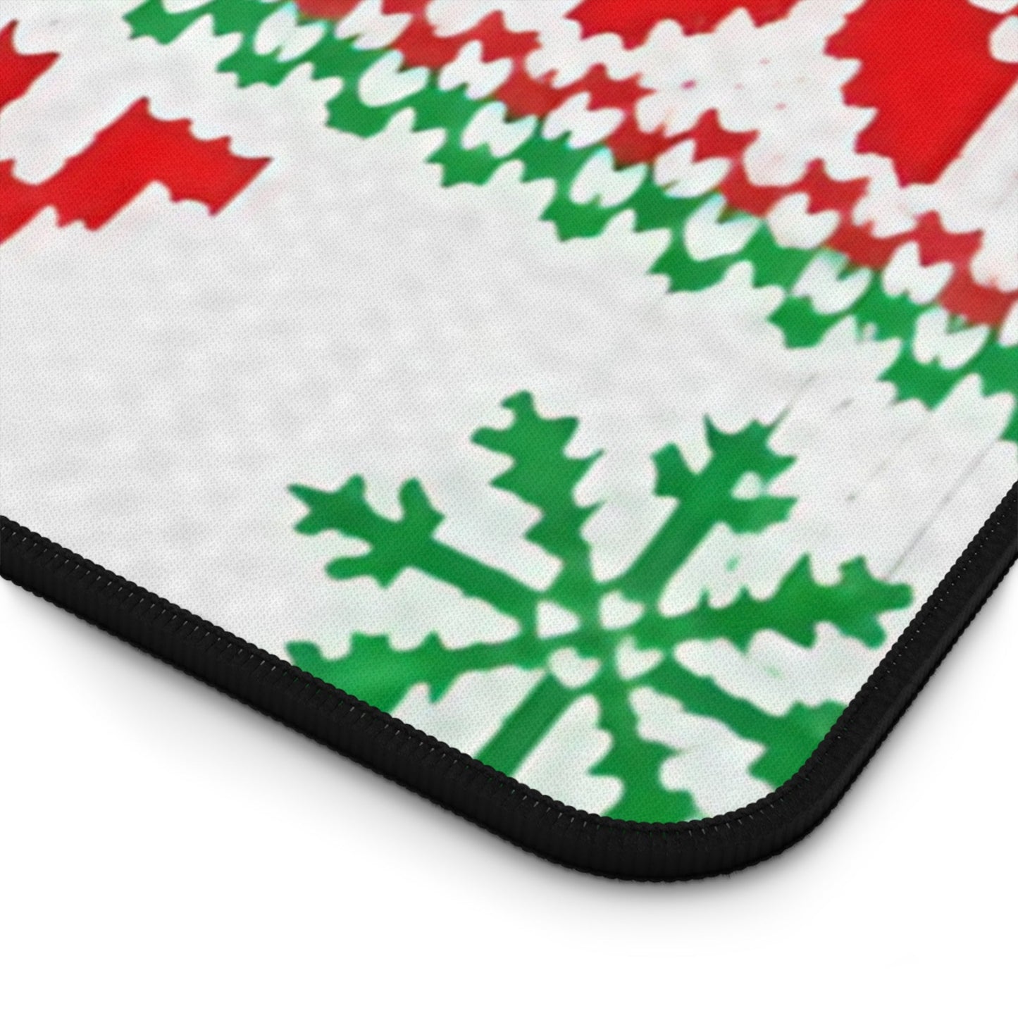 Close-up of ugly sweater inspired desk mat with festive red and green holiday patterns and stitched edges, non-slip bottom visible