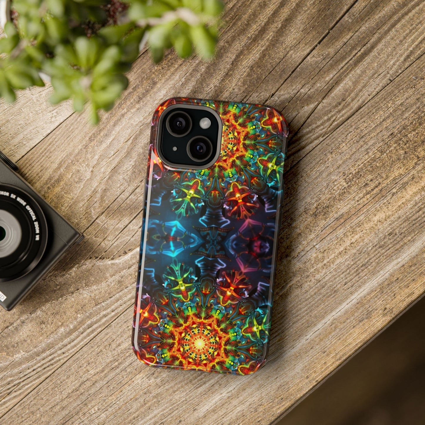 Colorful abstract kaleidoscope design iPhone case with vibrant pattern and dual-layer protection on wooden surface