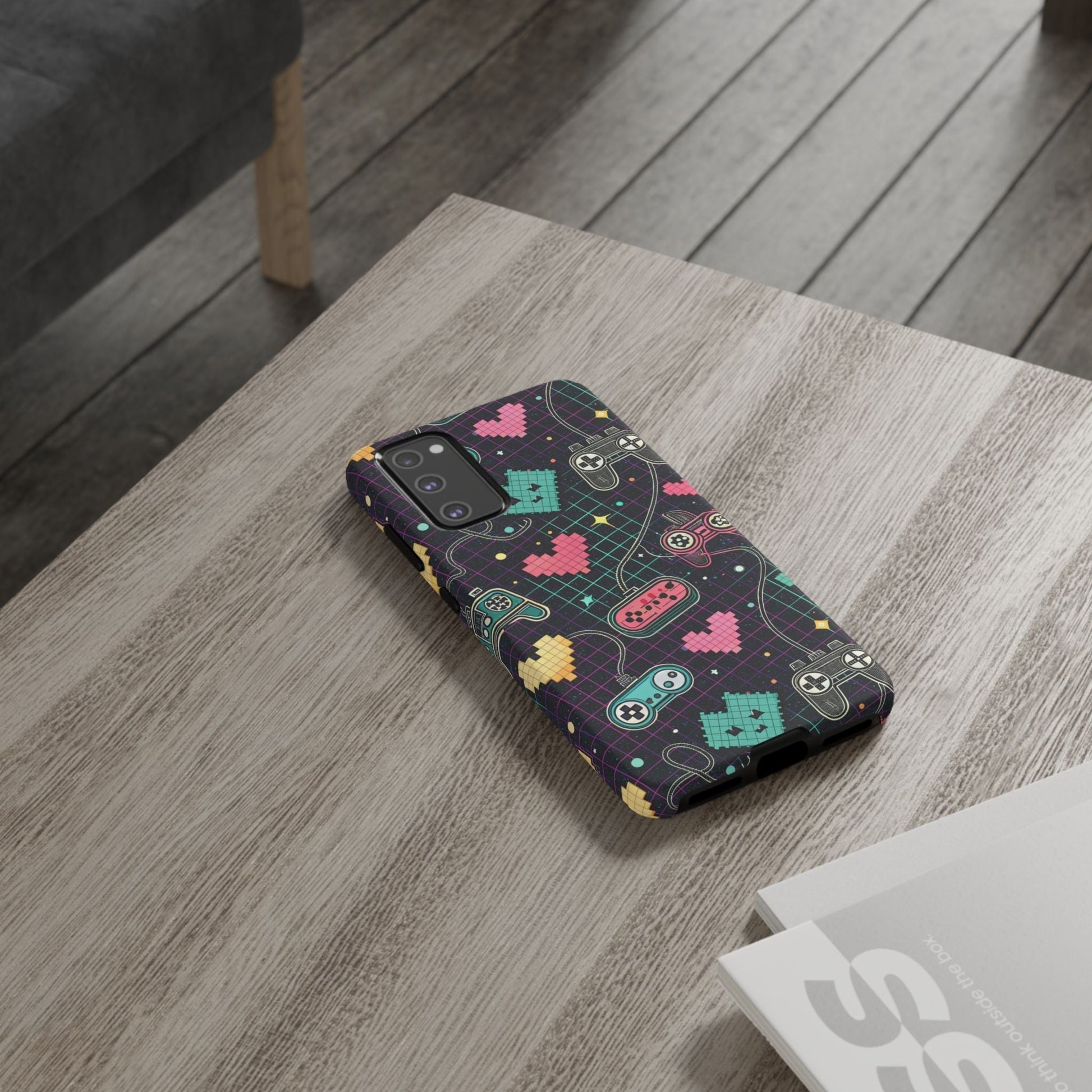 Samsung Galaxy phone with retro gamer tough case featuring colorful pixelated gaming icons and heart designs on a dark background