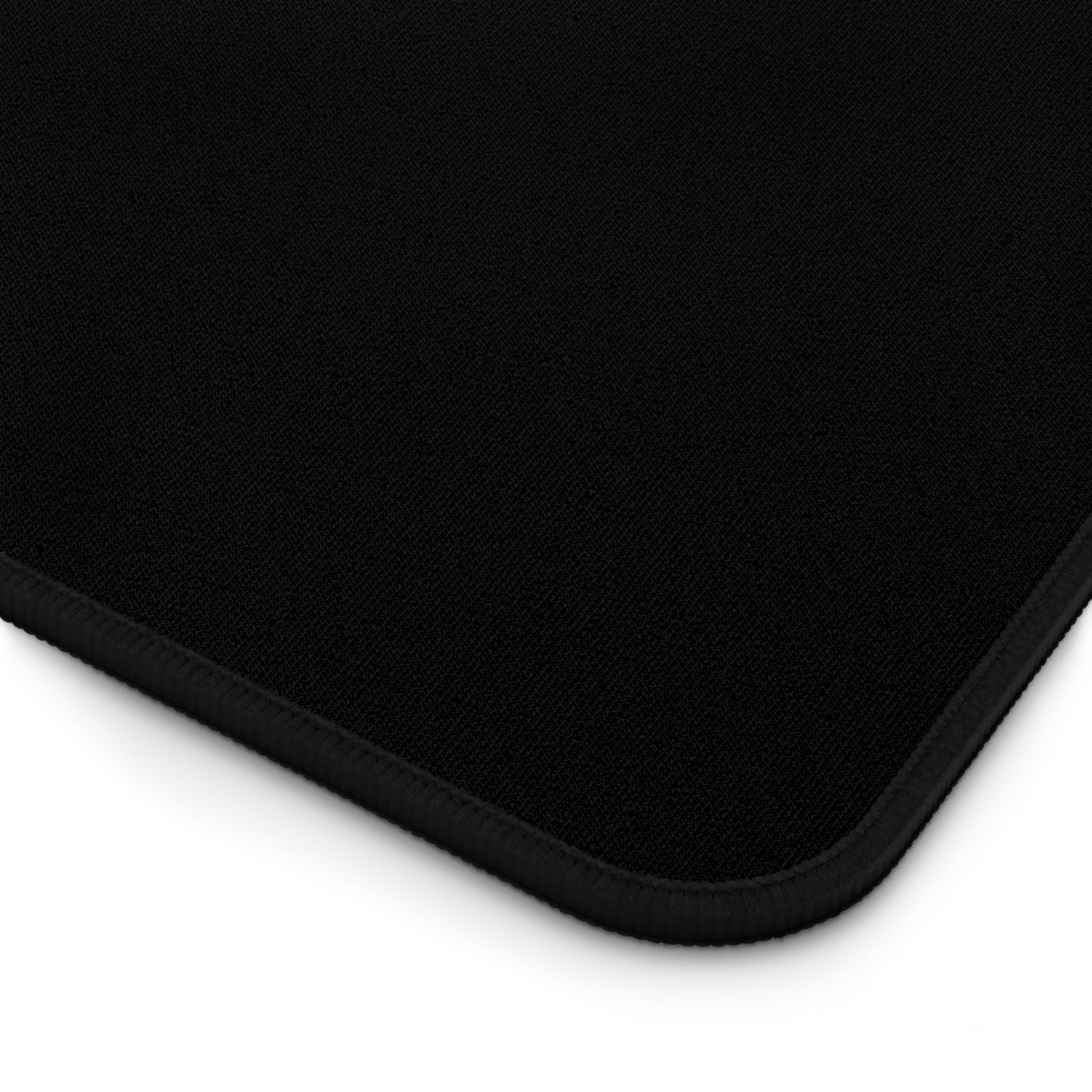 Close-up of black desk mat corner with hemmed edges and textured surface, non-slip bottom, part of Funny Santa Desk Mat collection