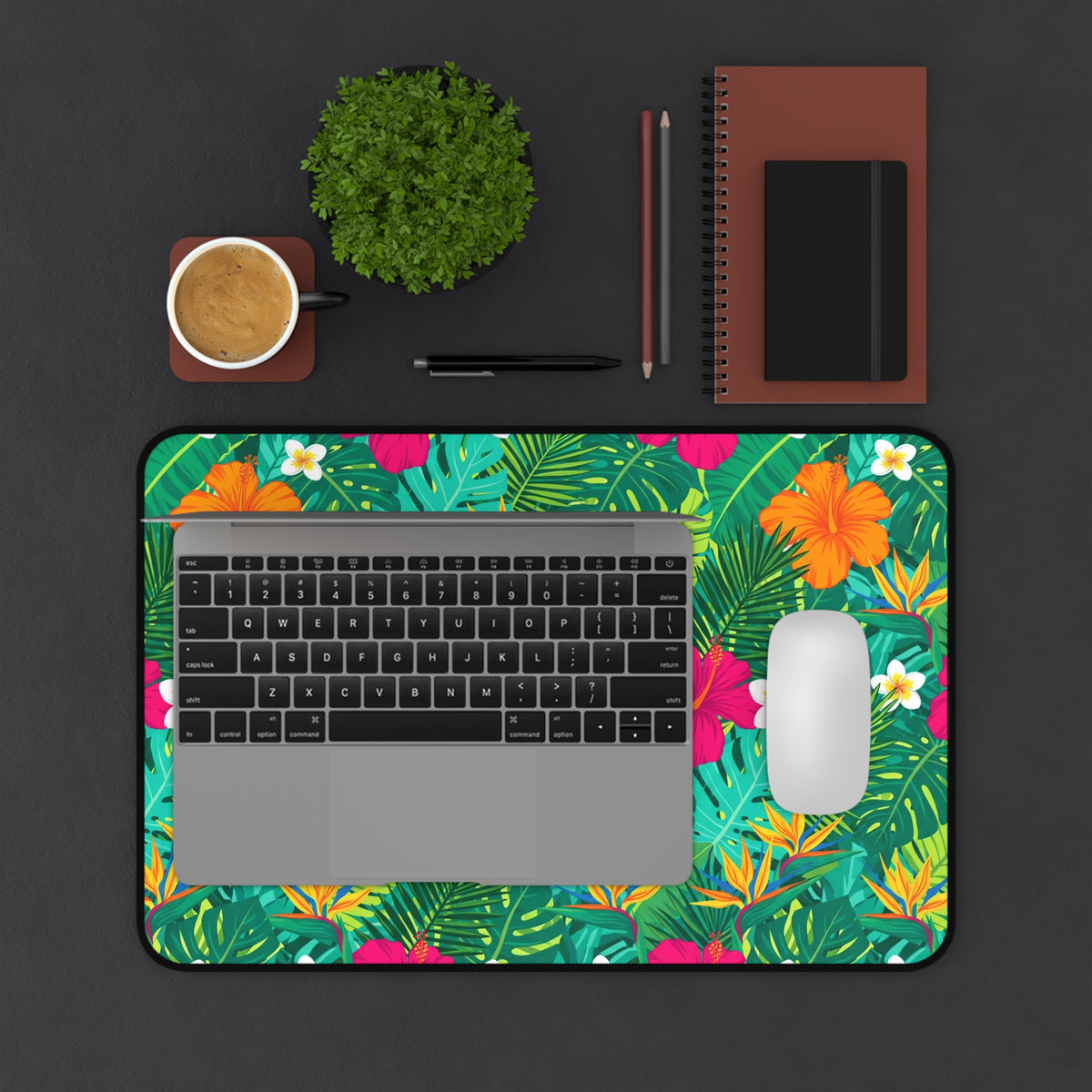 Tropical floral print mousepad with laptop, mouse, coffee, plant, and notebooks.