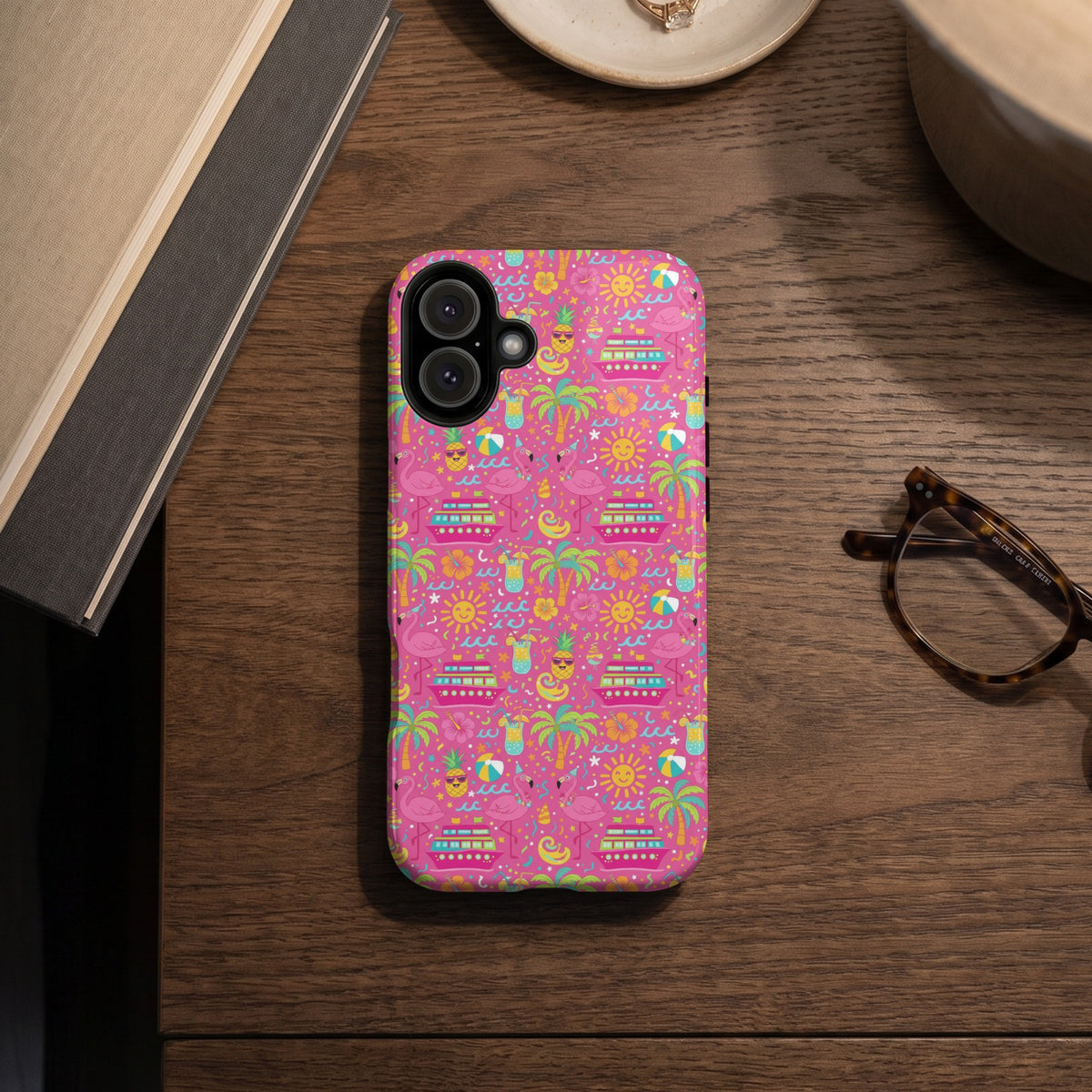 Pink phone case with a repeating pattern of cruise ships, flamingos, suns, and tropical drinks.