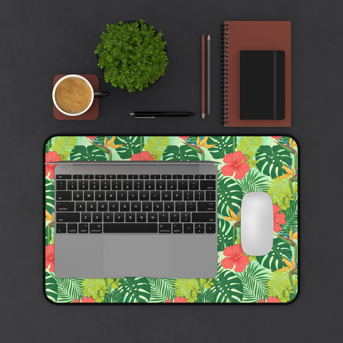 Floral mousepad with laptop, coffee, plant, and notebooks on desk.