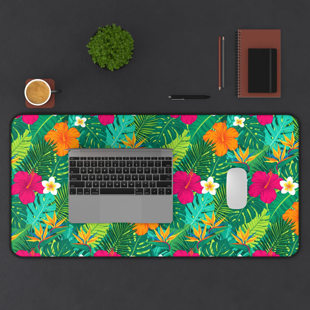 Tropical floral desk mat with laptop, mouse, coffee cup, plant, and notebook.